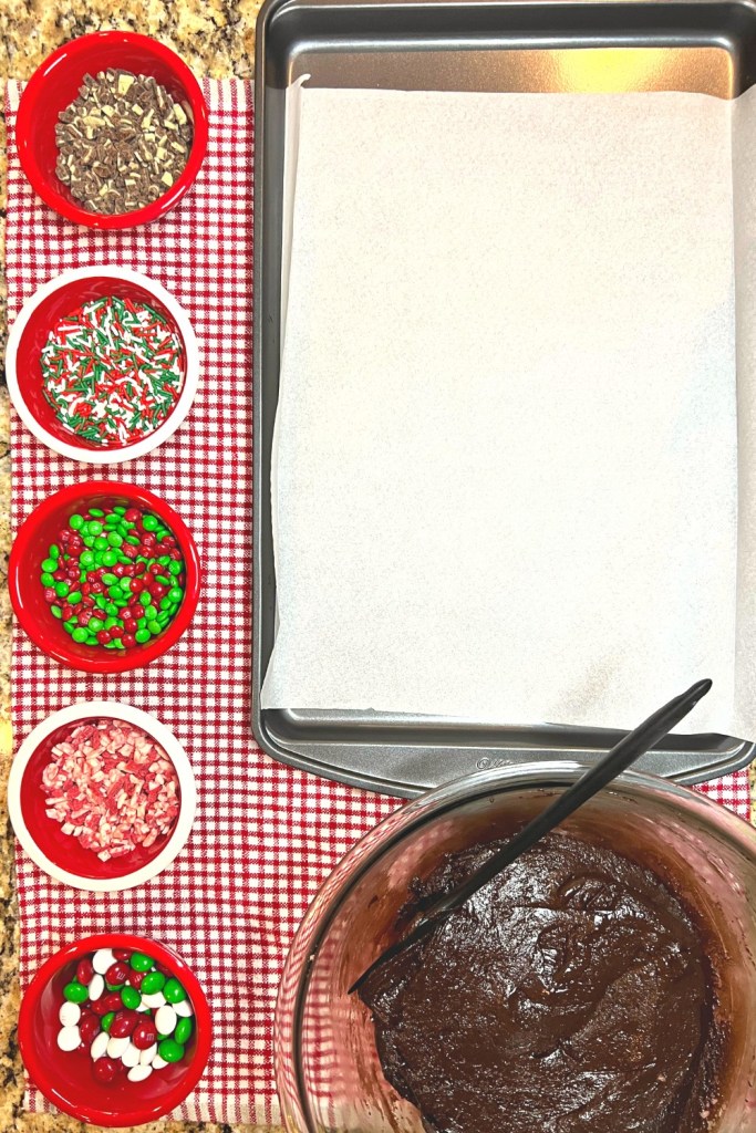 Christmas cookie station: toppings in bowls, cookie dough in bowl, and baking tray lined with parchment paper